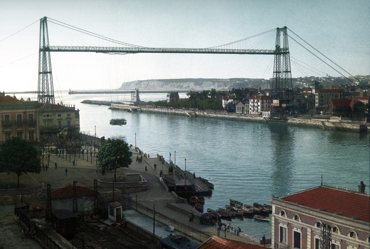 El Puente Vizcaya en 1934, pocos años antes de ser dinamitado y perder la viga. / Foto Autoridad Portuaria de Bilbao. Coloreada para el calendario de 2024.